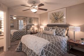 Phoenix apartment for rent - Ahwatukee, AZ, Apartments Near I-10 - Pacific Bay Club - Inviting Bedroom With Plush Bed, Patterned Bedding, Mirrored Closet Doors, Bedside Lamps, Ceiling Fan, And Neutral Wall Art.