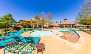Austin apartment for rent - Wells Branch, TX, Garden-Style Apartments Near Katherine Fleischer Park - The Nine on Shoreline - Resort-Style Pool With Sundeck, Blue Lounge Chairs, Small Tables, Trees, and Clubhouse.
