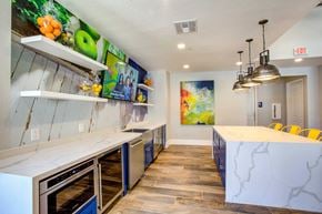 Phoenix apartment for rent - Apartments for Rent in North Phoenix, AZ - Ironhorse at Tramonto - Resident Lounge with a Kitchen, Floating Display Shelves, Wall-Mounted TV, Large Granite Kitchen Island with Seating, and Hanging Light Fixtures.