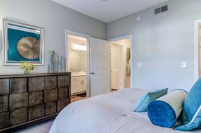 Woodstock apartment for rent - Pet-Friendly Apartments in Woodstock, GA – Lea Woodstock – bedroom with bed and dresser with view of bathroom and hallway