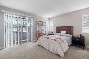 San Jose apartment for rent - A bedroom with a large bed and a window with blinds.