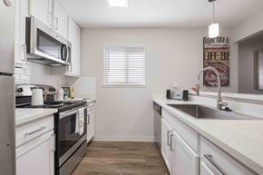 San Jose apartment for rent - A kitchen with white cabinets and a black stove top oven.