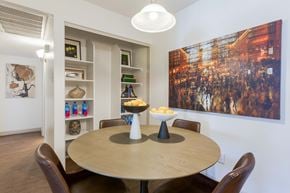Scottsdale apartment for rent - Dog-Friendly Apartments in Scottsdale, AZ - The Sycamore at Scottsdale - Dining Area With Round Table, Built-In Shelving, Pendant Light, Wall Art, And Warm Wood Style Flooring.