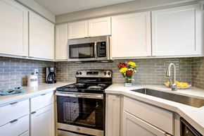 Phoenix apartment for rent - Luxury Apartments North Phoenix - Village At Lakewood - A Kitchen With Stainless Steel Appliances Including A Dishwasher, Oven, And Built-In Microwave, Quartz Countertops, And Tile Backsplash.