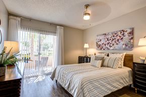 Phoenix apartment for rent - Pet-Friendly Apartments in Phoenix AZ - Village at Lakewood - Bedroom with Wood-Style Flooring and Access to Patio