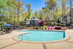 Marietta apartment for rent - Apartments in Marietta Georgia for Rent – Wood Pointe Apartments - A large swimming pool surrounded by trees and a building in the background.