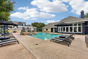 Round Rock apartment for rent - A pool area with sun loungers and a building in the background.