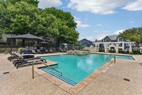 Round Rock apartment for rent - A pool surrounded by trees and chairs.