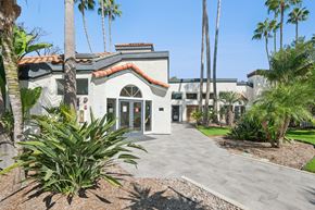 San Clemente apartment for rent - A building with a red tile roof and palm trees in front.