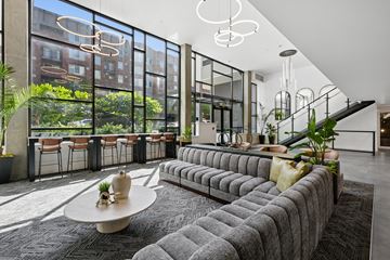 Seattle apartment for rent - A modern living room with a large grey sofa and a round table with a vase on it.