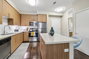 Santa Clara apartment for rent - Two-Bedroom Apartments in Santa Clara, CA - Villas on the Boulevard - Modern Kitchen With Wood Cabinetry, White Countertops, Stainless Steel Appliances, Island Storage, And Dark Wood Flooring.