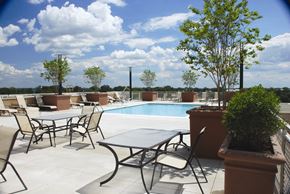 Arlington apartment for rent - A table and chairs are set up on a patio with a pool in the background.