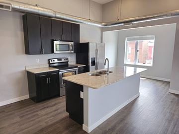 St. Louis apartment for rent - A kitchen with black cabinets and a granite countertop.