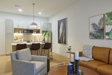 Fayetteville apartment for rent - A living room with a grey armchair, a brown leather sofa, and a dining table with chairs.