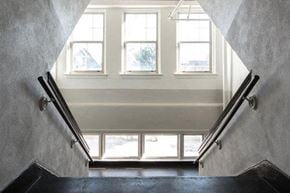 St. Louis apartment for rent - A staircase with a black railing leads to a bright room with three windows.
