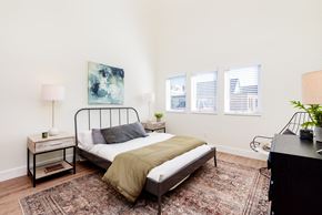 St. Louis apartment for rent - A bedroom with a bed, nightstand, and a painting on the wall.