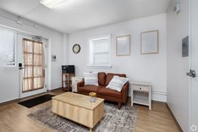 St. Louis apartment for rent - A living room with a brown couch, a wooden coffee table, and a small white table.