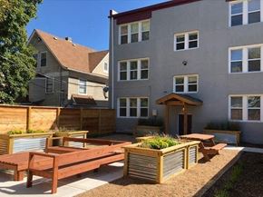Kansas City apartment for rent - A grey building with a wooden bench in front of it.
