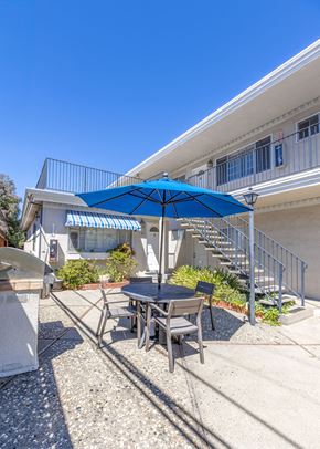 San Jose apartment for rent - a patio with a table and umbrella in front of a building