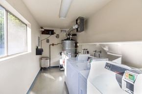 Santa Clara apartment for rent - A clean, white industrial laundry room with a row of washers and dryers.