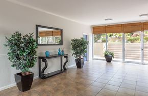 San Jose apartment for rent - A room with a mirror, a bench, and potted plants.