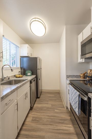 Sunnyvale apartment for rent - A kitchen with white cabinets and a black fridge.