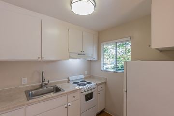 San Jose apartment for rent - a kitchen with white cabinets and a sink and a refrigerator