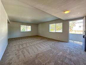San Carlos apartment for rent - A spacious room with a carpeted floor and two windows.