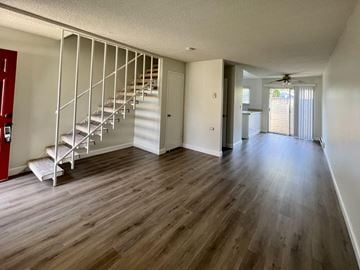 San Jose townhouse for rent - an empty living room with a staircase and hard wood floors