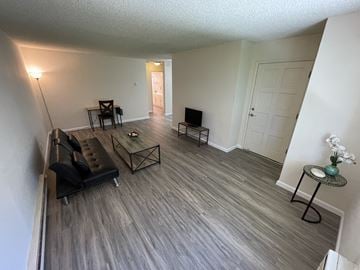 San Jose apartment for rent - A living room with a black couch and a wooden floor.