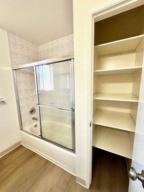 San Jose apartment for rent - A white bathroom with a walk-in shower and a white cabinet with shelves.