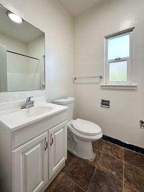 San Jose apartment for rent - A white toilet sits in a bathroom next to a sink and a mirror.