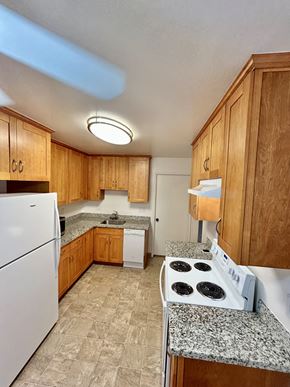San Jose triplex for rent - A kitchen with a white refrigerator, wooden cabinets, and a granite countertop.
