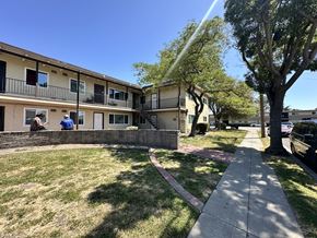 Newark apartment for rent - A sunny day in a residential area with apartment buildings and a sidewalk.