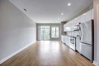 A kitchen with white appliances and wooden floors.