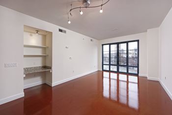 A large empty room with a brown floor and white walls.