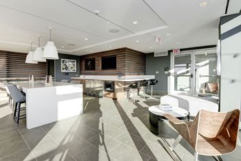 A kitchen and living room with a bar and chairs 