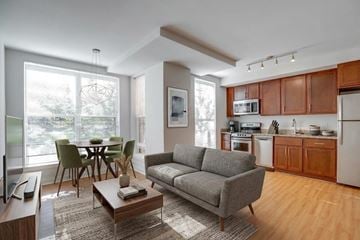 Washington townhouse for rent - A modern living room with a grey sofa, a wooden coffee table, and a dining table with chairs.