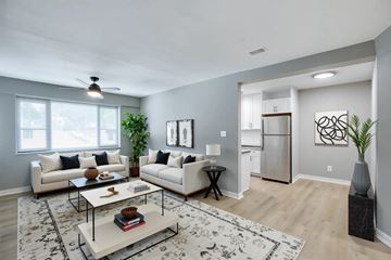 Washington apartment for rent - A modern living room with a white sofa set, a coffee table, and a kitchen in the background.