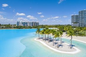 North Miami apartment for rent - A large swimming pool surrounded by palm trees and a sandy area.