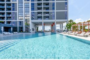Miami apartment for rent - A large swimming pool in front of a modern building.