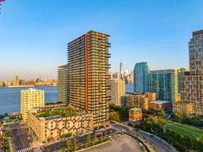 Jersey City apartment for rent - A cityscape with a prominent building in the foreground and a body of water in the background.