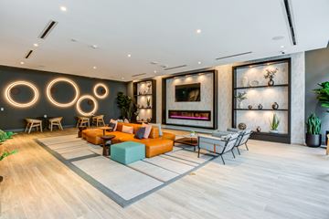Miami apartment for rent - A modern living room with a fireplace and a large painting on the wall.