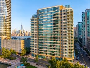 Jersey City apartment for rent - A tall building with many windows is in the foreground of a cityscape.