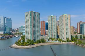 Jersey City apartment for rent - A cityscape with a body of water in the foreground and buildings in the background.