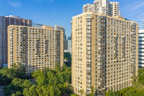 Jersey City apartment for rent - A large building with many windows is surrounded by trees.