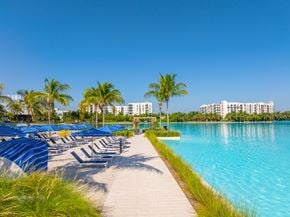 North Miami apartment for rent - A row of blue sun loungers are on the left of a walkway leading to a body of water.