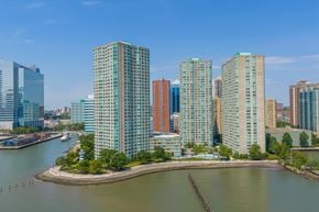 Jersey City apartment for rent - A cityscape with a body of water in the foreground and buildings of various heights in the background.