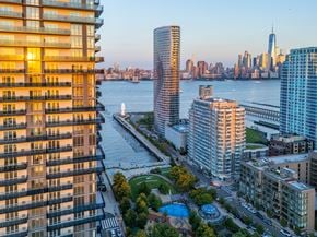 Jersey City apartment for rent - A cityscape with a river and a tall building in the background.