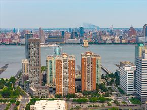 Jersey City apartment for rent - A cityscape with a body of water in the foreground and a bridge in the background.